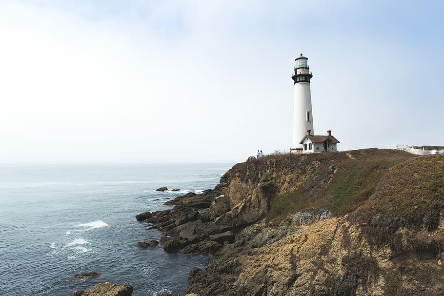 white lighthouse on hill near ocean, white lighthouse near cliff and ocean during daytime HD wallpaper