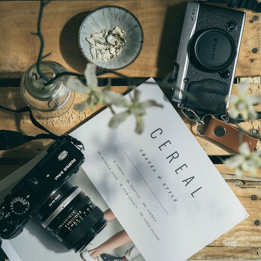 white printer paper between two black DSLR cameras, black Fujifilm DSLR camera on Cereal Travel and Style book