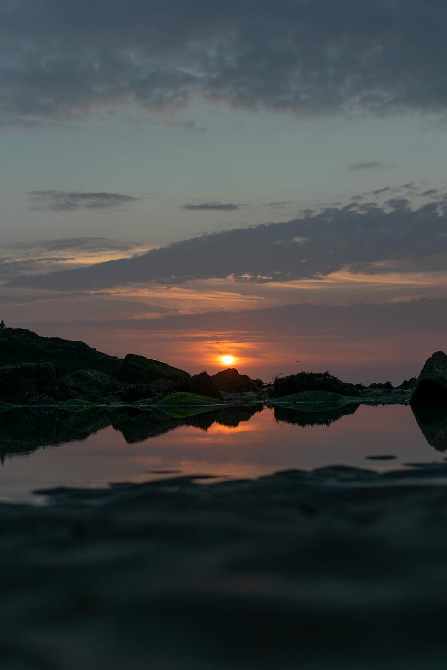 body of water near rock formation, silhouette of mountains during sunset HD wallpaper