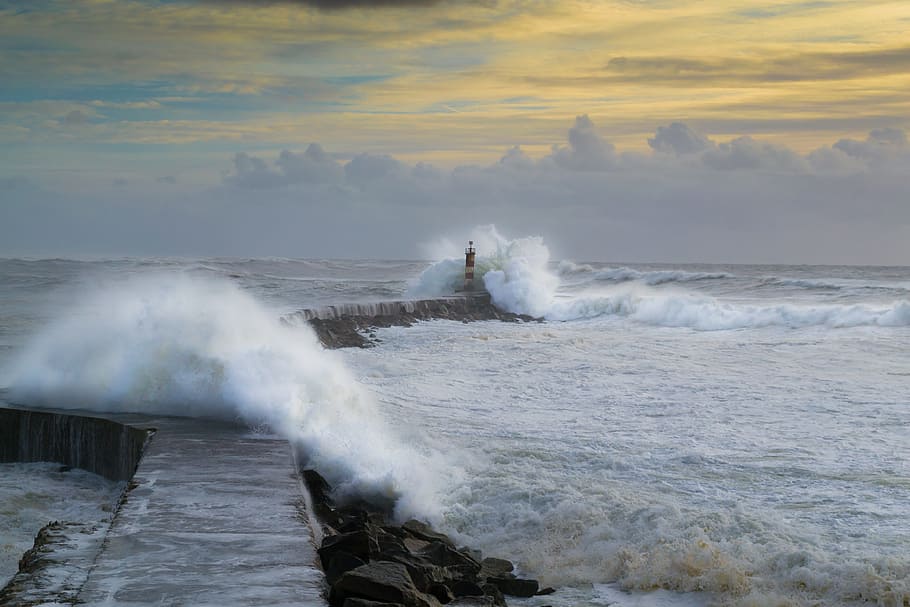 red and white wave of water hitting lighthouse during daytime HD wallpaper