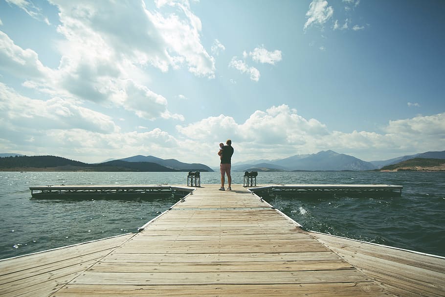 person in black top carrying a baby, child, clouds, dad, dock HD wallpaper