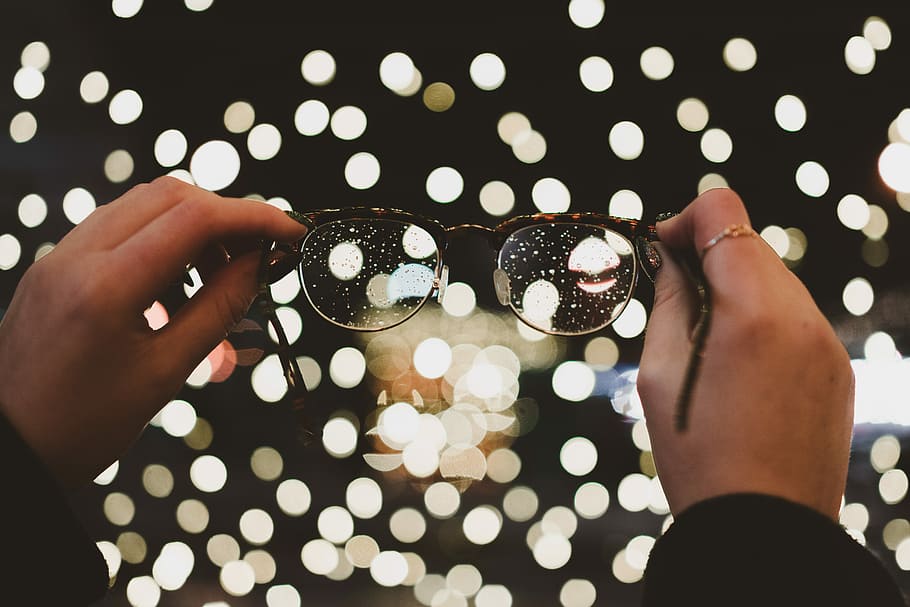 bokeh photography of eyeglasses, person holding eyeglasses in front of boke lights HD wallpaper