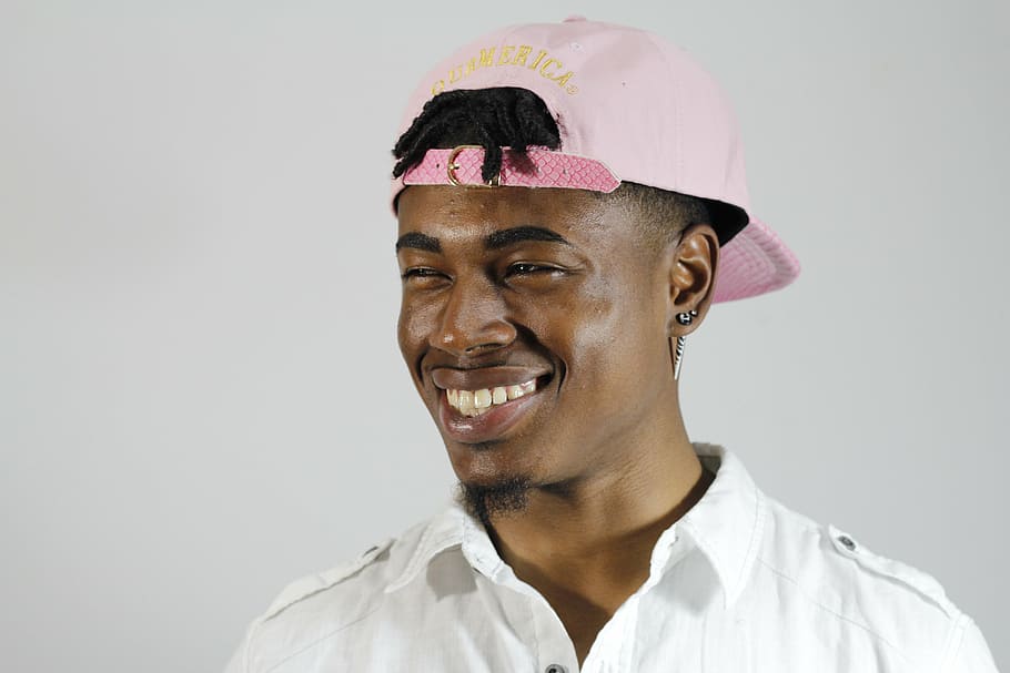 man wearing pink snapback cap looking towards left, rapper, happy