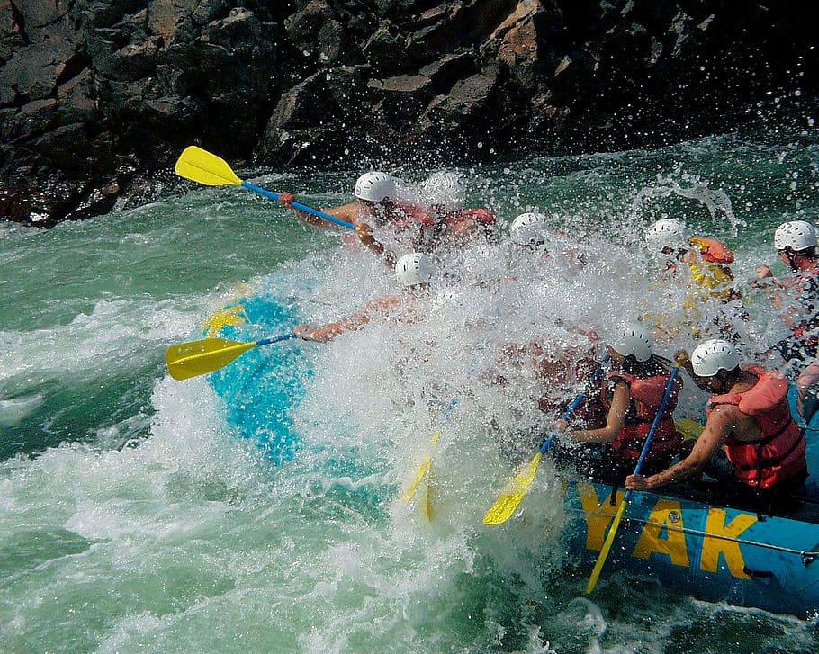 group of people paddling on inflatable raft at daytime, river rafting