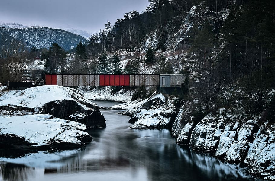 body of water between snow-covered rocks during daytime, bridge beside trees HD wallpaper