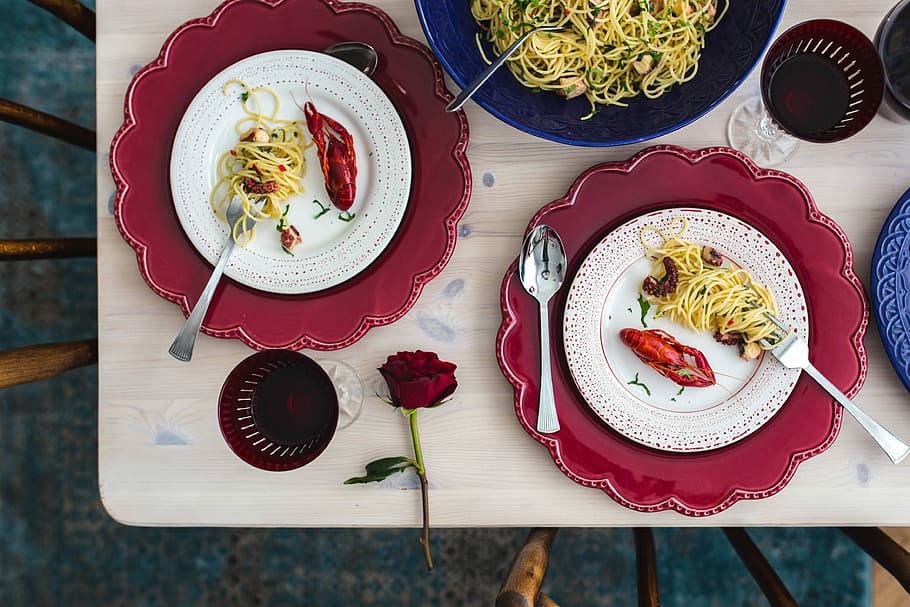 Fancy dinner with seafood pasta, crayfish and red wine by the table decorated with roses HD wallpaper