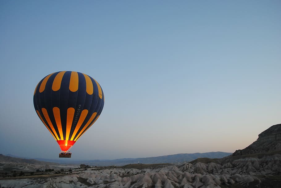 blue and yellow hot air balloon hovering above mountain, ballooning