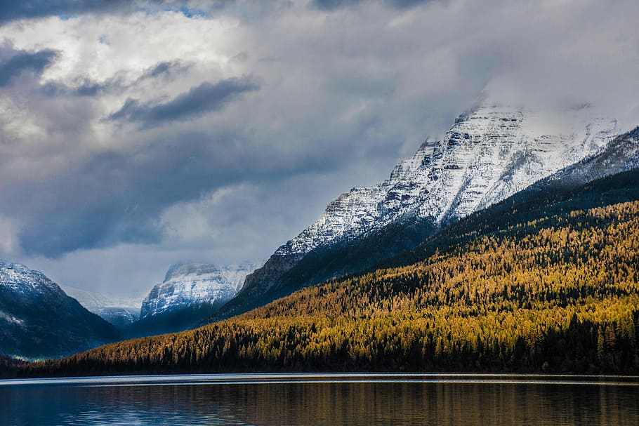 body of water near mountains, calm body of lake near yellow plants and glacier mountain under white cloud blue skies HD wallpaper