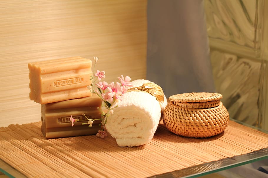 two soap bars near white face towel and brown basket on brown wooden table