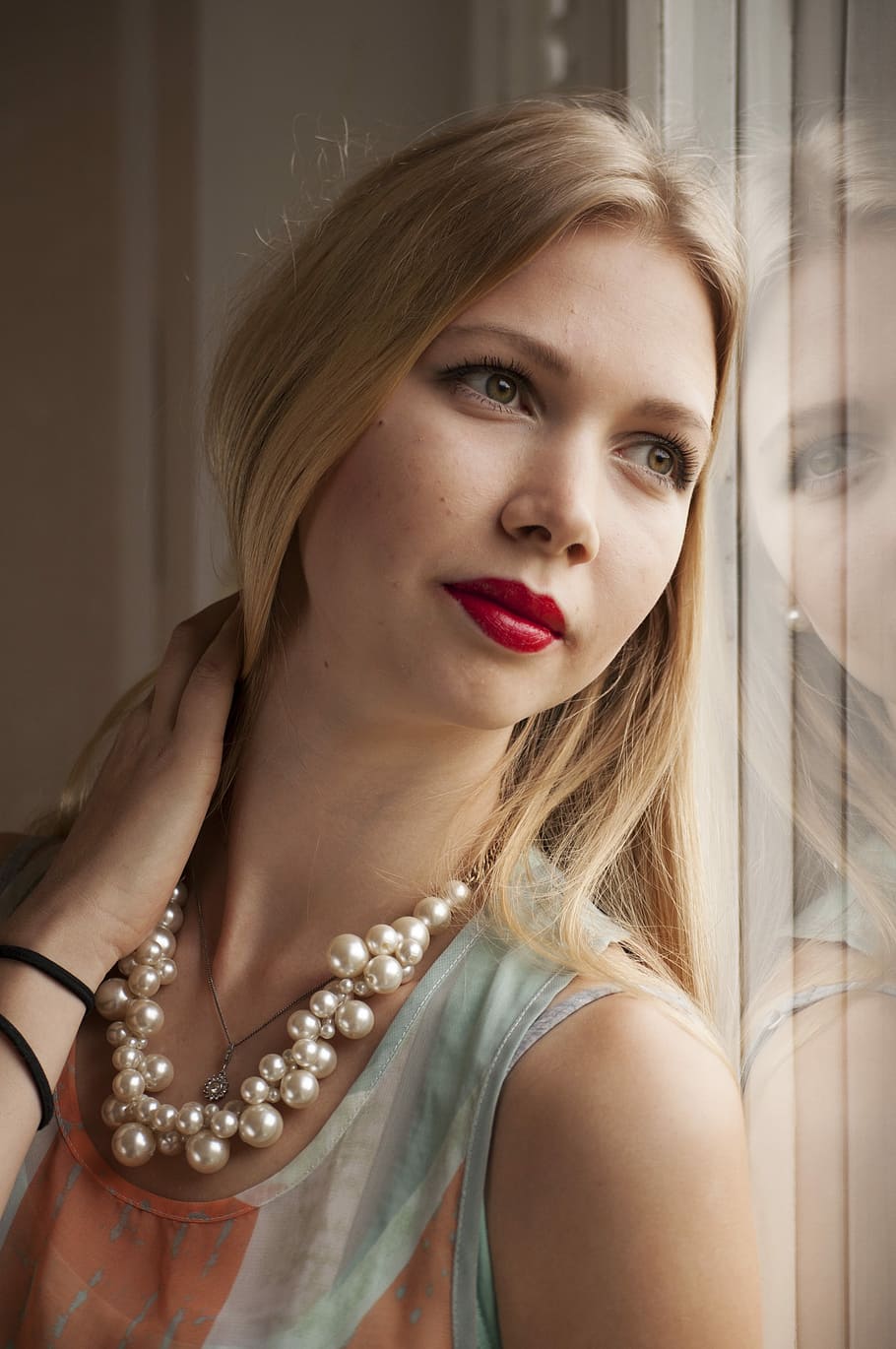 woman wearing teal and orange tank top leaning on glass wall