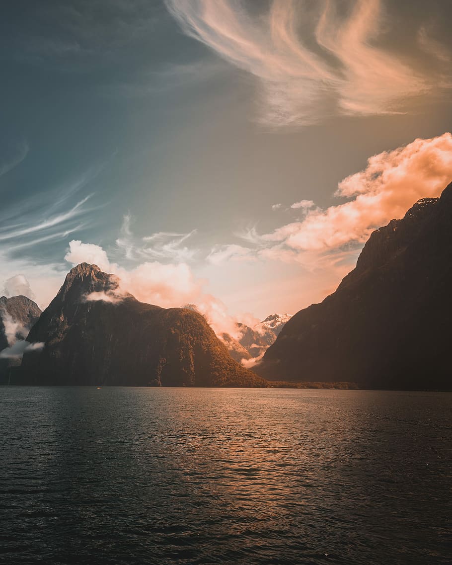 mountains near body of water during golden time, mountain near body of water under clear blue sky HD wallpaper