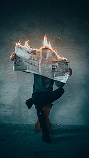 surrealism photography of person reading news paper in fire while sitting on stool, person holding burning newspaper HD wallpaper