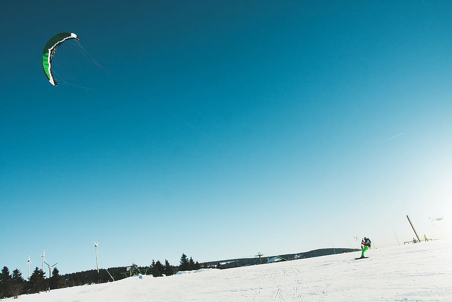 person holding paraglider standing on white snow covered hill at daytime HD wallpaper