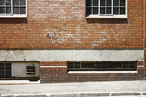 white spray paint texts printed on brown brick wall, brown bricked building with graffiti HD wallpaper