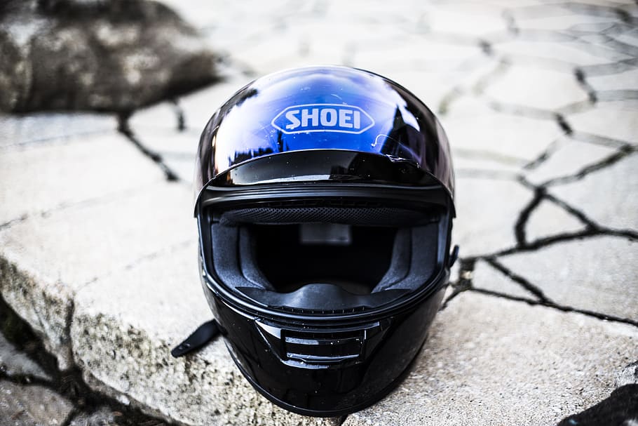 black Shoei full-face helmet on top of grey stone fragment, motorbike