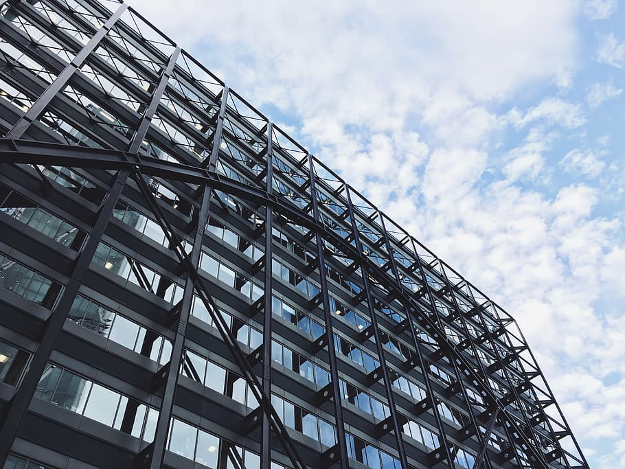 low-angle photography of black and gray concrete building under white sky HD wallpaper