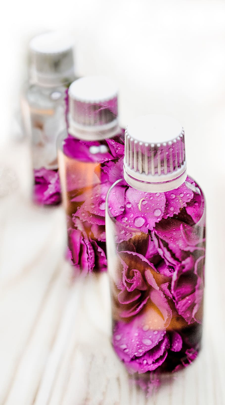 macro photography of three pink and white floral plastic bottles