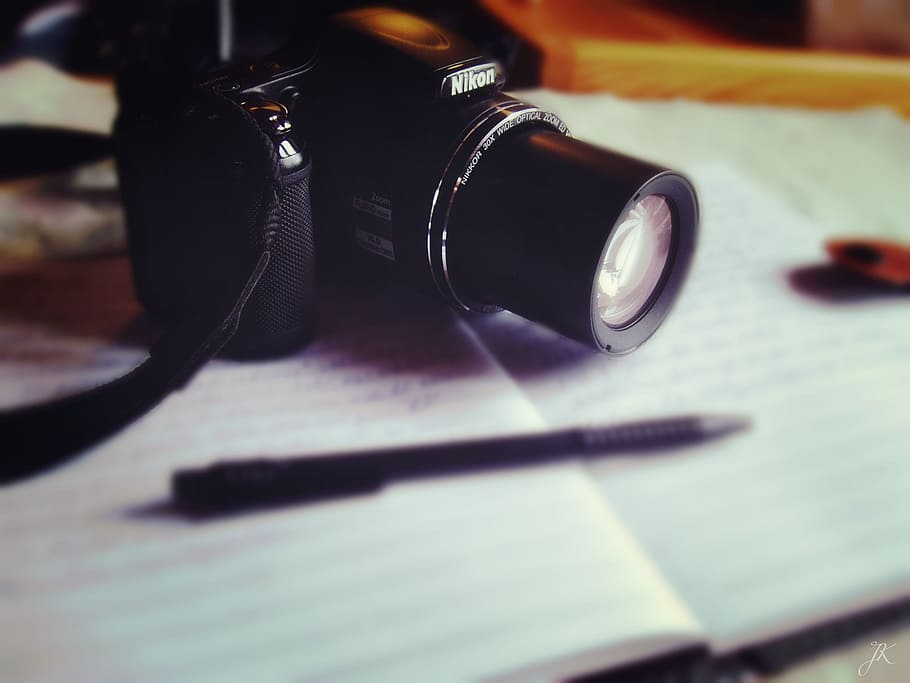 selective focus of black Nikon bridge camera on printed notebook HD wallpaper