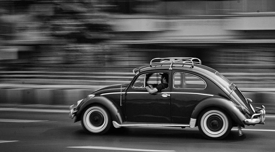 grayscale photo of moving beetle car, grayscale photo of man riding on beetle car on road HD wallpaper