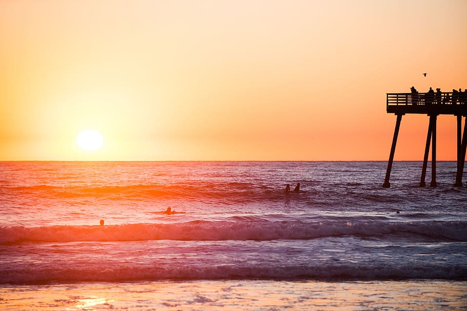 sunset, beach, water, waves, ocean, sea, pier, swimming, people HD wallpaper