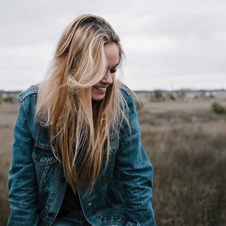 close up photo of women's wearing blue chambray jacket near brown grass during daytime HD wallpaper
