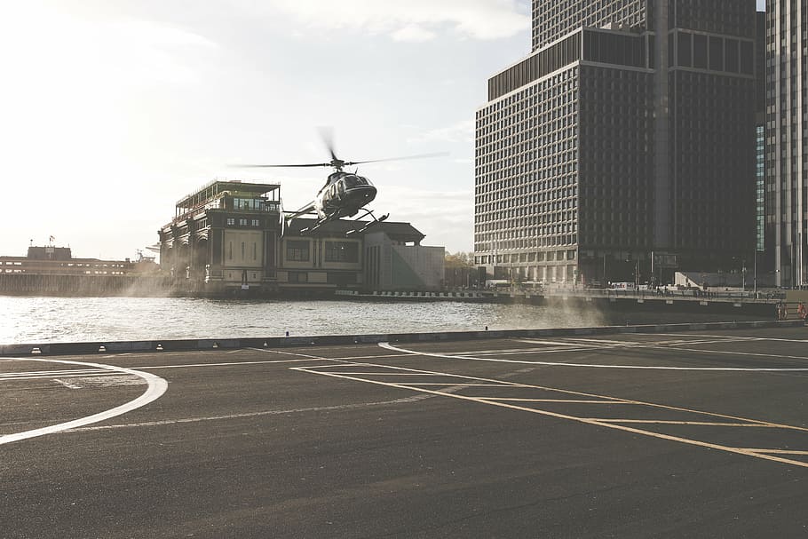grayscale photo of helicopter about to land near buildings HD wallpaper
