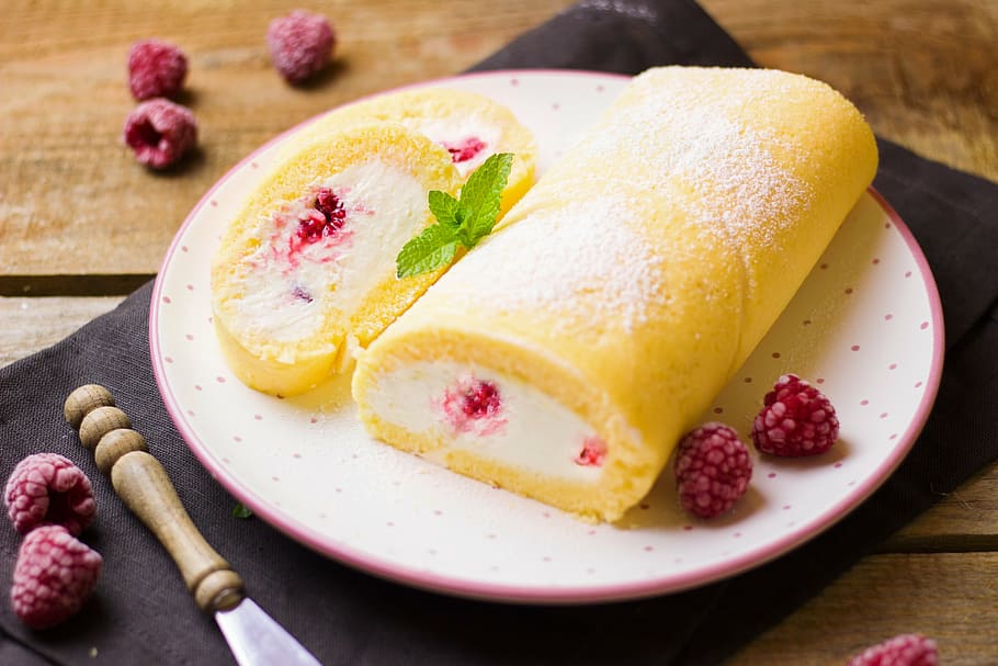 round white and pink ceramic plate with yellow bread, roulade