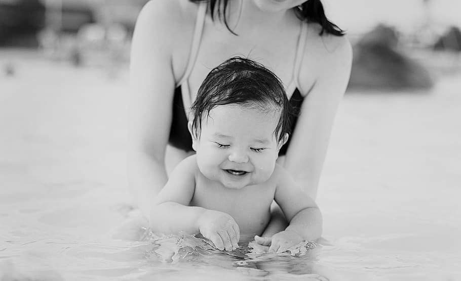woman carrying baby on in body of water, pool, fun, summer, happy