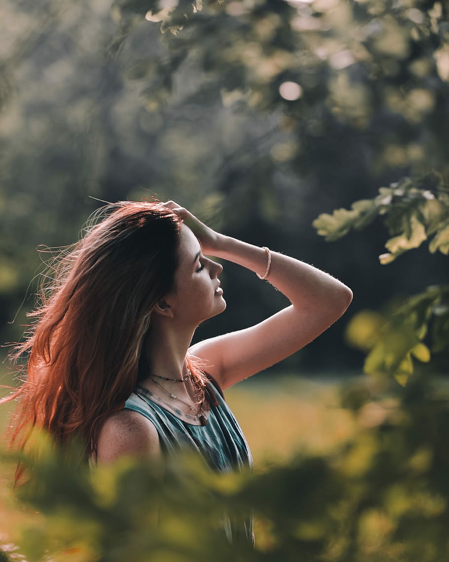 selective focus photography of woman holding her hair standing near trees, woman combing her hair beside tree, HD wallpaper