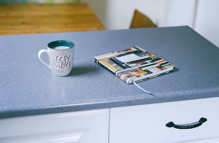 gray and white ceramic mug beside multicolored covered book, mug on drawer HD wallpaper