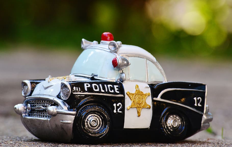 selective focus photography of white and black police car scale model on pavement