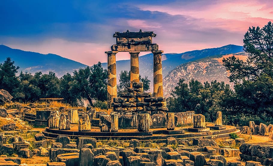 column ruins surrounded by trees and stone head, Oracle At Delphi, HD wallpaper