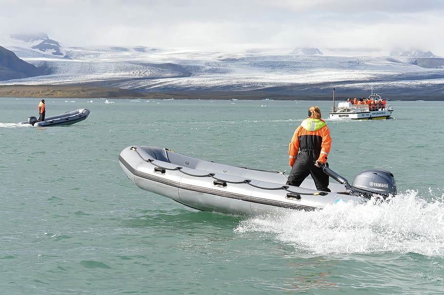 Jökulsárlón- Glacial River Lagoon, man in black and orange suit riding on boat during daytime