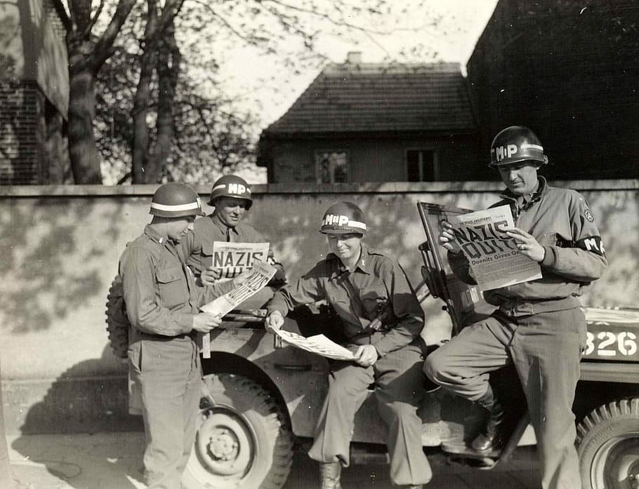 US military policemen read about the German surrender ending World War II in Europe