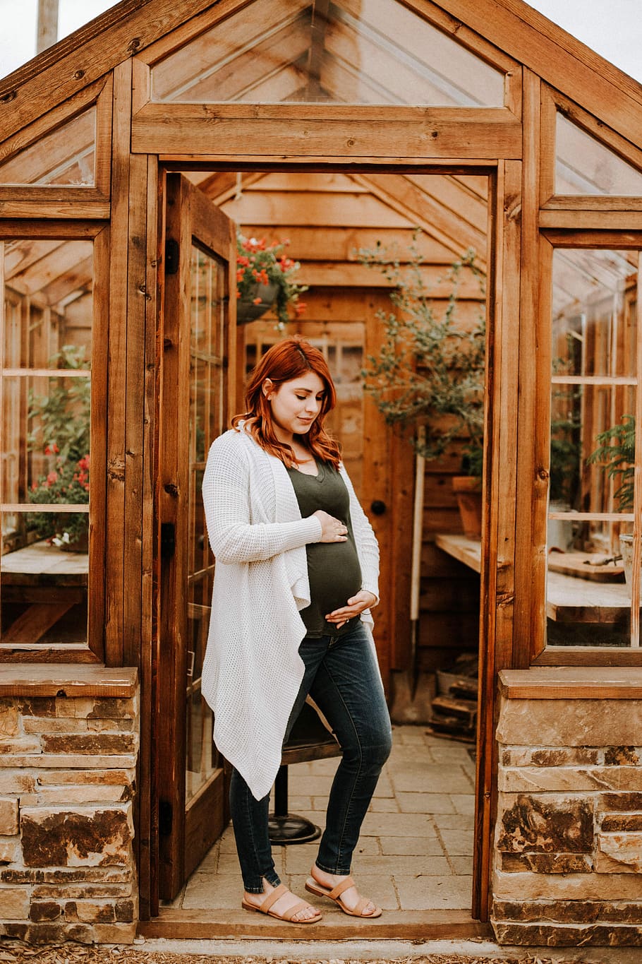 pregnant woman holding her tummy while standing near garden shed, pregnant woman at the green house doorway HD wallpaper