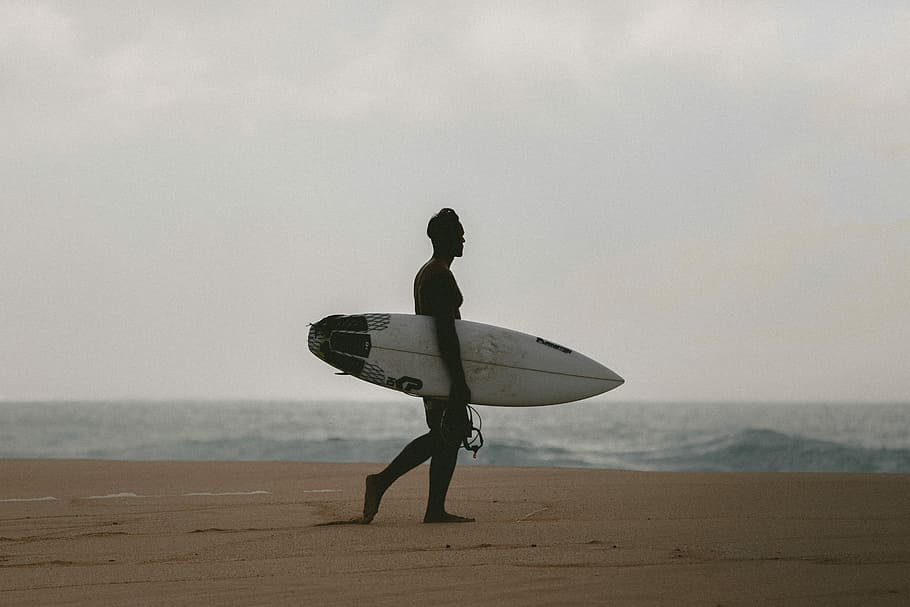 man walking on beach shore, man carrying surfboard on shoreline HD wallpaper