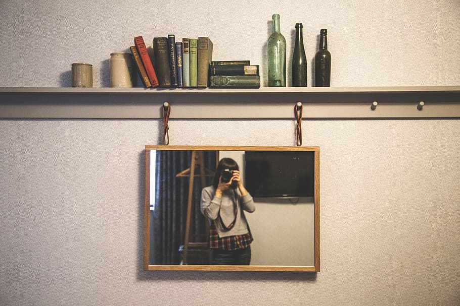 brown framed mirror hanged on beige wall, people, woman, camera