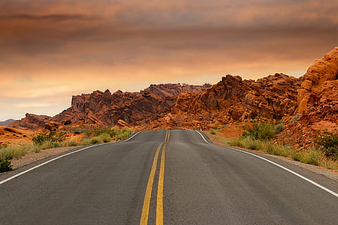gray concrete road with gree grass along, mountains, sunset HD wallpaper