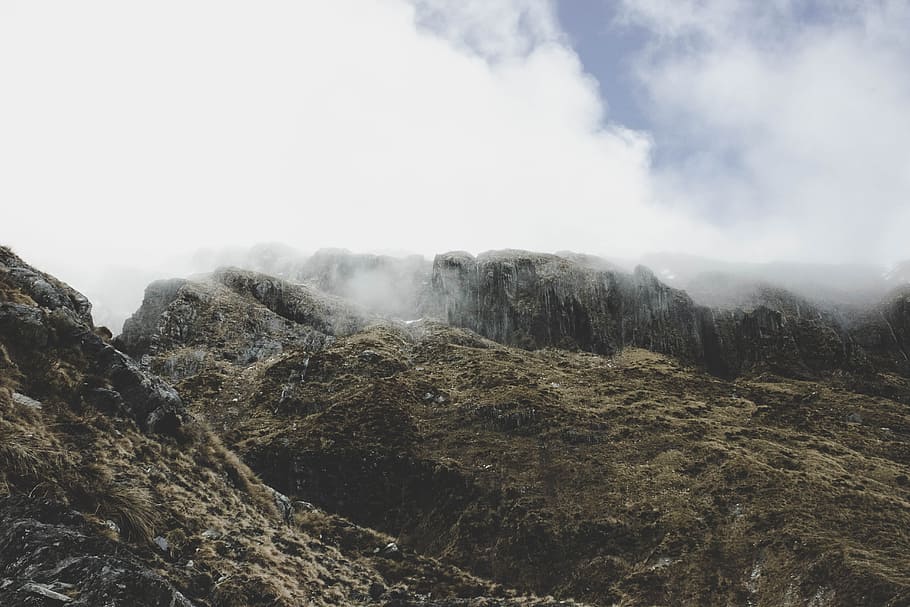 gray rocky mountain at daytime, landscape photography of mountain covered with fog HD wallpaper