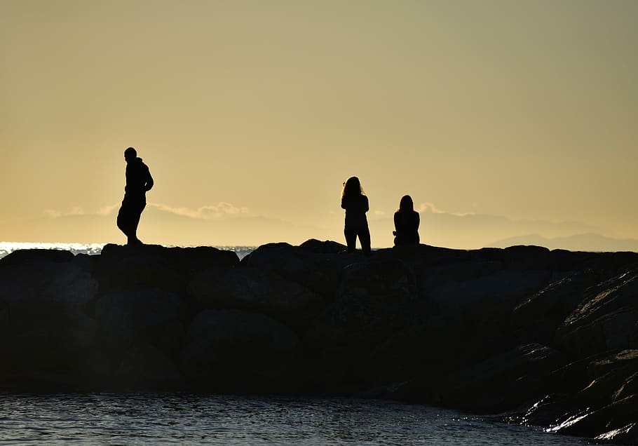 silhouette people near sea during sunset, silhouette photo of people on rock near body of water during dawn HD wallpaper