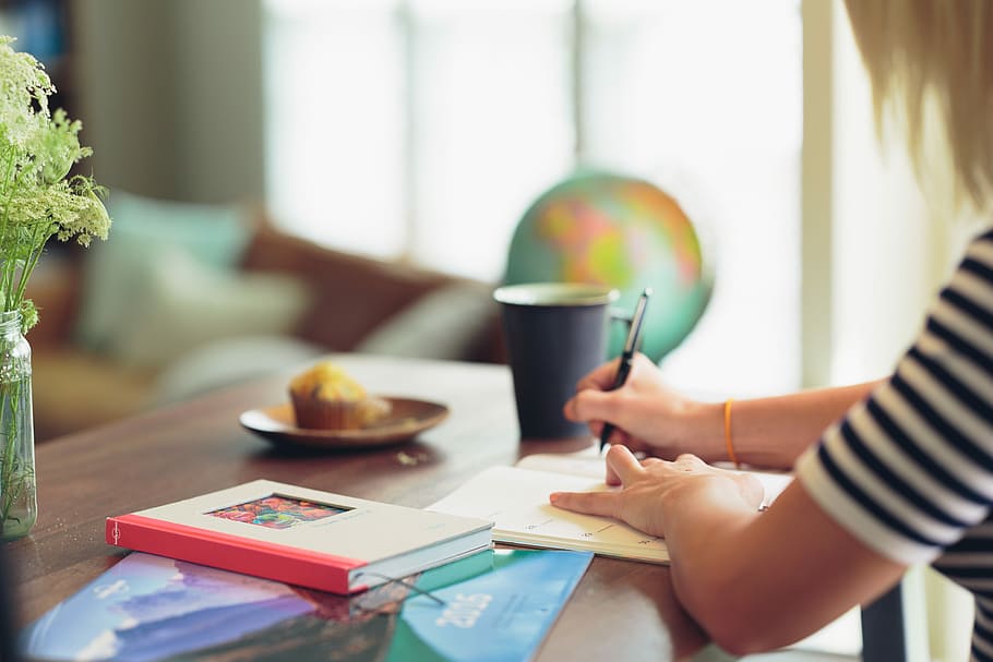 shallow focus photography of person in white and black striped top writing on white paper, woman writing on book HD wallpaper