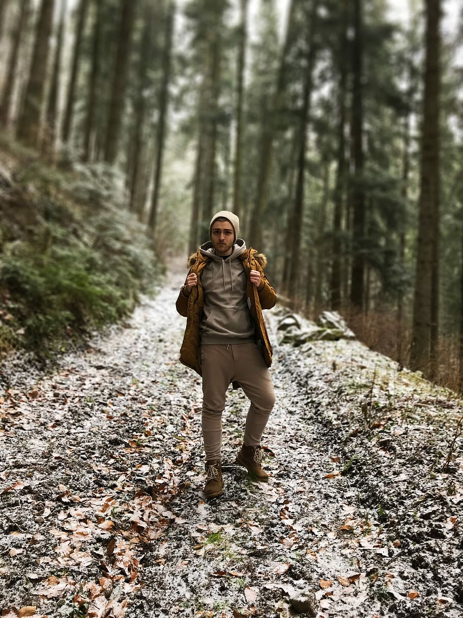 selective focus photography of man on forest, man standing on trail between tree HD wallpaper