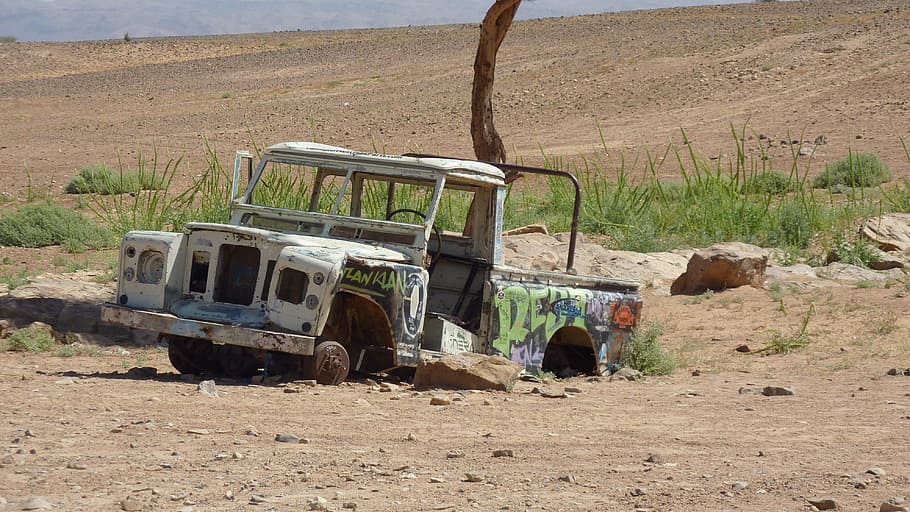 wrecked and abandoned white Land Rover Defender SUV on dessert during daytime