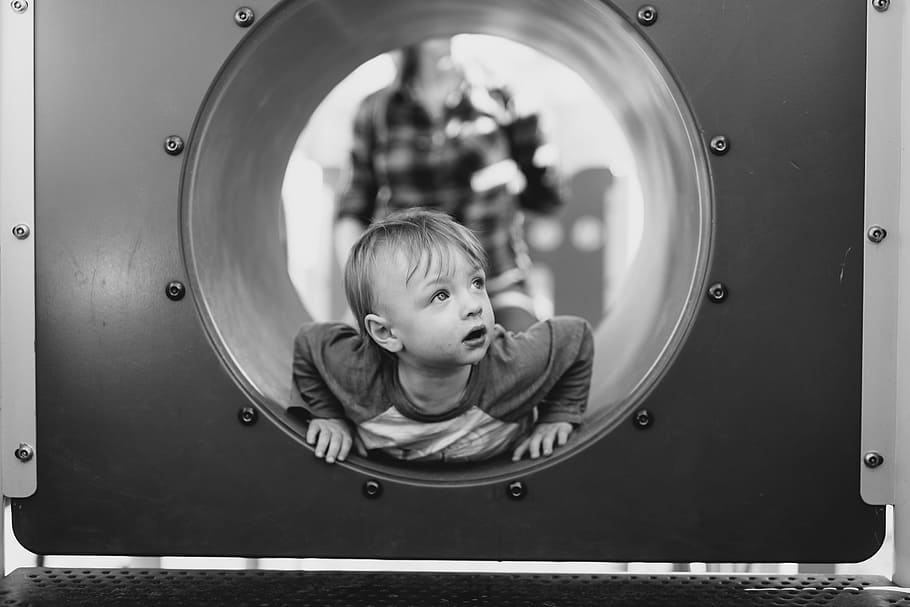 grayscale photo of child in hole, grayscale photo of boy lying on tunnel HD wallpaper