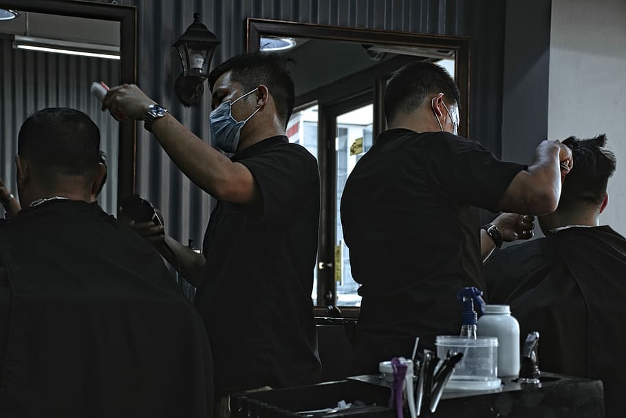 man hair cutting hair of man, two man in black shirt doing haircut during daytime