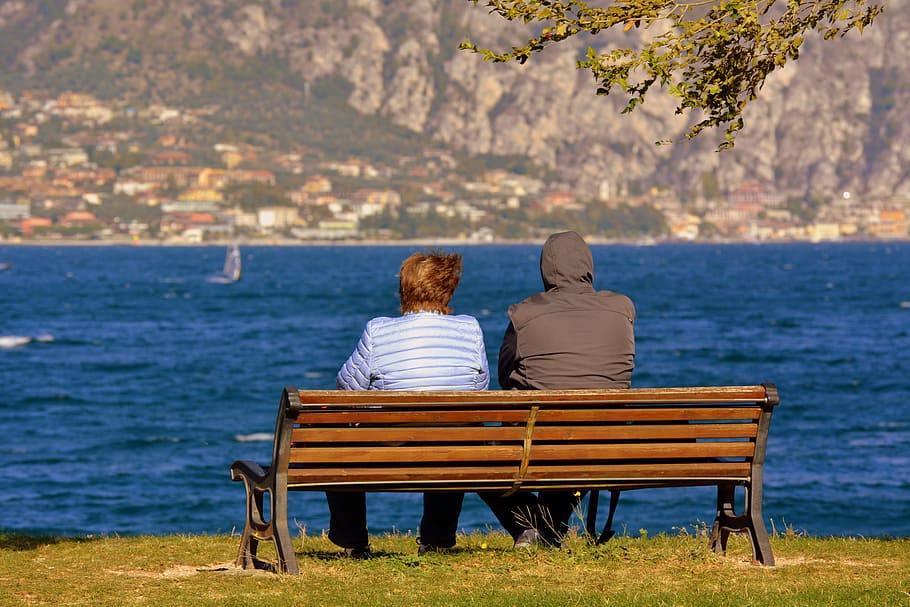 man and woman sitting near calm body of water, solitude, couple HD wallpaper