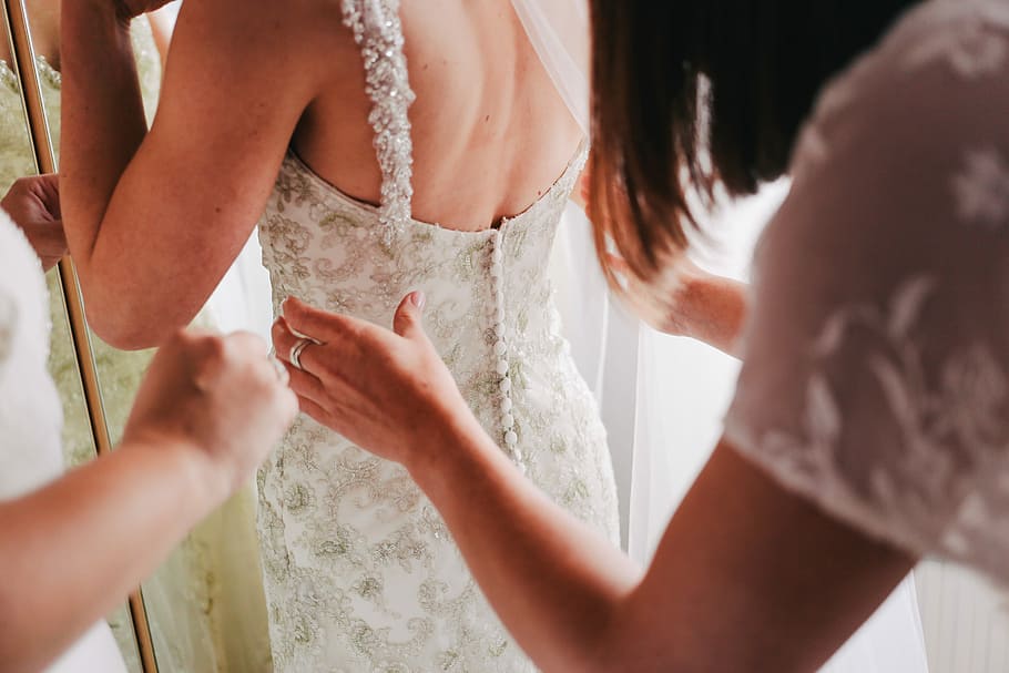 Bride and Bridesmaids Getting Ready for Wedding, woman wearing white and silver lace sleeveless wedding gown