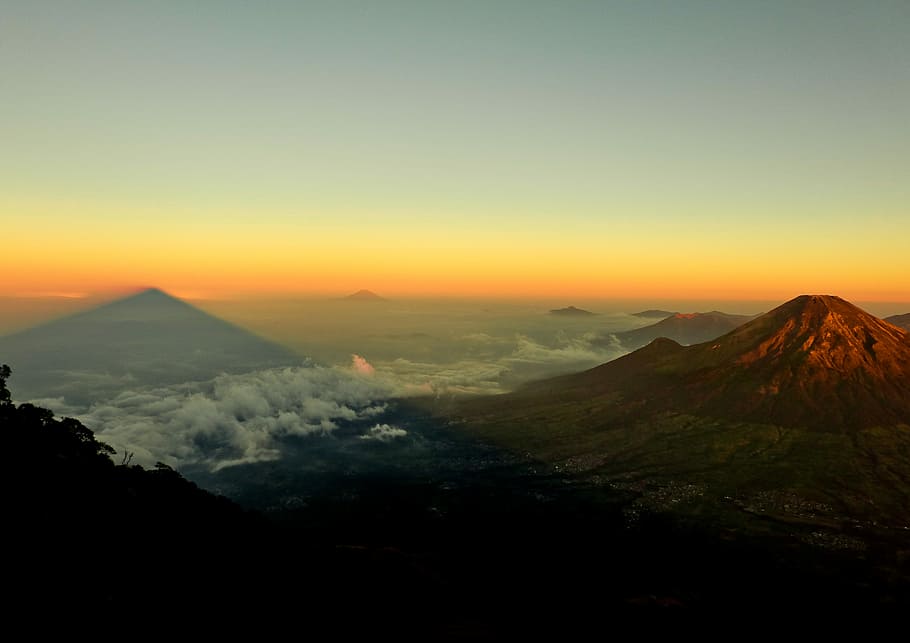 aerial photo of mountain near land covered by white clouds at golden hour, mountain during sunset