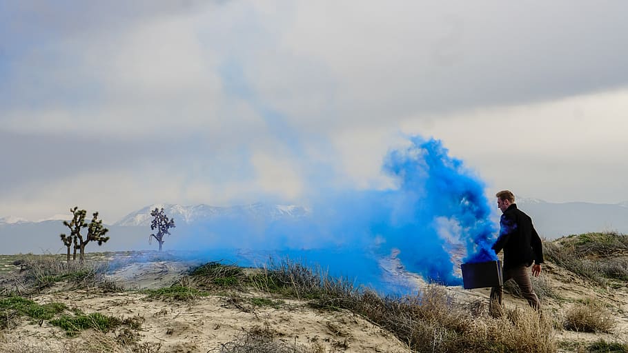 man carrying a case with blue smoke oozing from it while walking, HD wallpaper