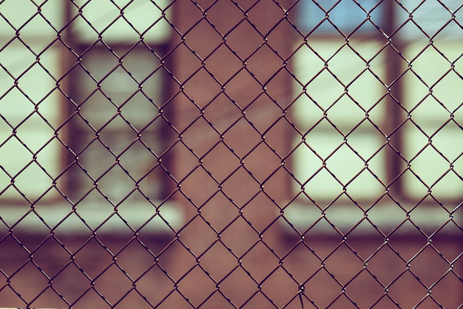 black chain-link fence, brown building structure behind gray steel chain link fence